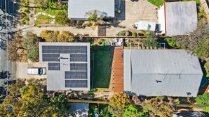 A residential area with a house featuring a solar panel array, a covered outdoor area, and a vehicle parked nearby. - Sunset Surf Retreats  500m to Beach Pet Friendly with Spa (Jan Juc)
