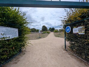 A dirt path leading to a garden entrance with a sign welcoming visitors. - Le Refuge de Césarine - CARNAC (CARNAC)