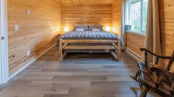 A wooden interior with a bed, a bench, and a window.