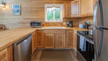 A kitchen with wooden cabinets, a stainless steel refrigerator, a microwave, and a sink.