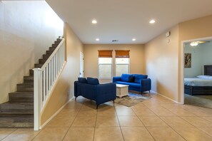 A living room with a staircase, a blue sofa, and a bed. - The Lindenthal | Family Friendly 5BR | Fenced Yard | Sleeps 10 (Tucson)