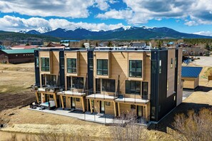 A modern multi-story building with large windows and a flat roof, surrounded by a mountainous landscape. - 3 Bedroom Modern Townhome - Pet Friendly, Private Hot Tub, Walk to Restaurants (Fraser)