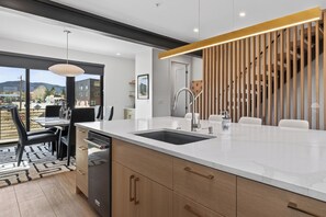 A modern kitchen with a large island, a built-in dishwasher, and a view through the glass door. - 3 Bedroom Modern Townhome - Pet Friendly, Private Hot Tub, Walk to Restaurants (Fraser)