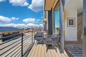 A balcony with a view of the sky and buildings, a table with chairs, and a framed picture on the wall. - 3 Bedroom Modern Townhome - Pet Friendly, Private Hot Tub, Walk to Restaurants (Fraser)
