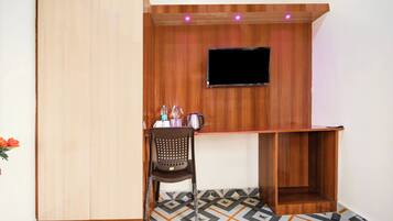 A room with a wooden TV stand, a small seating area, and a patterned floor.