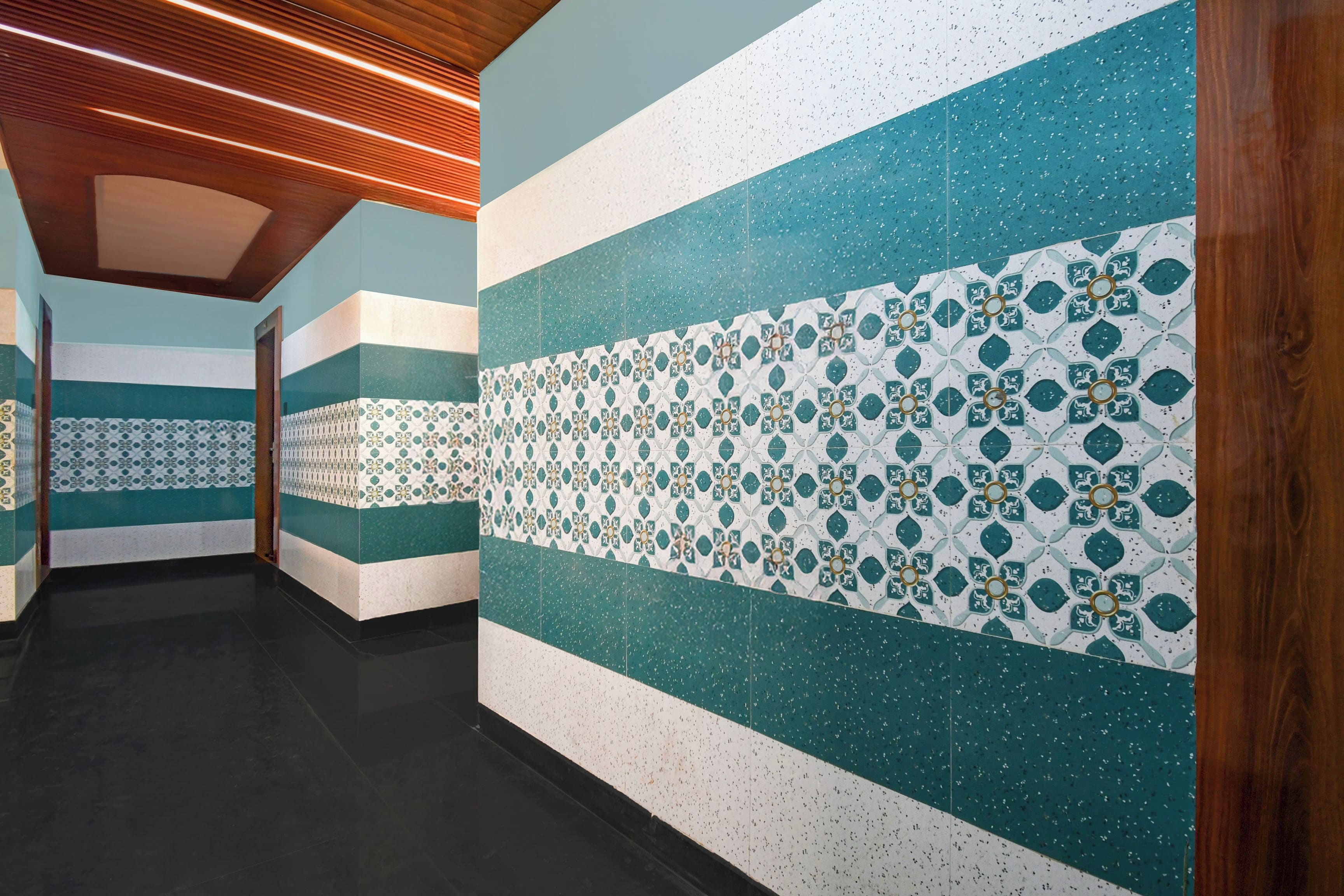 A corridor with patterned wall tiles and wooden ceiling panels.