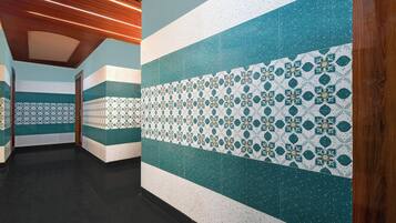 A corridor with patterned wall tiles and wooden ceiling panels.