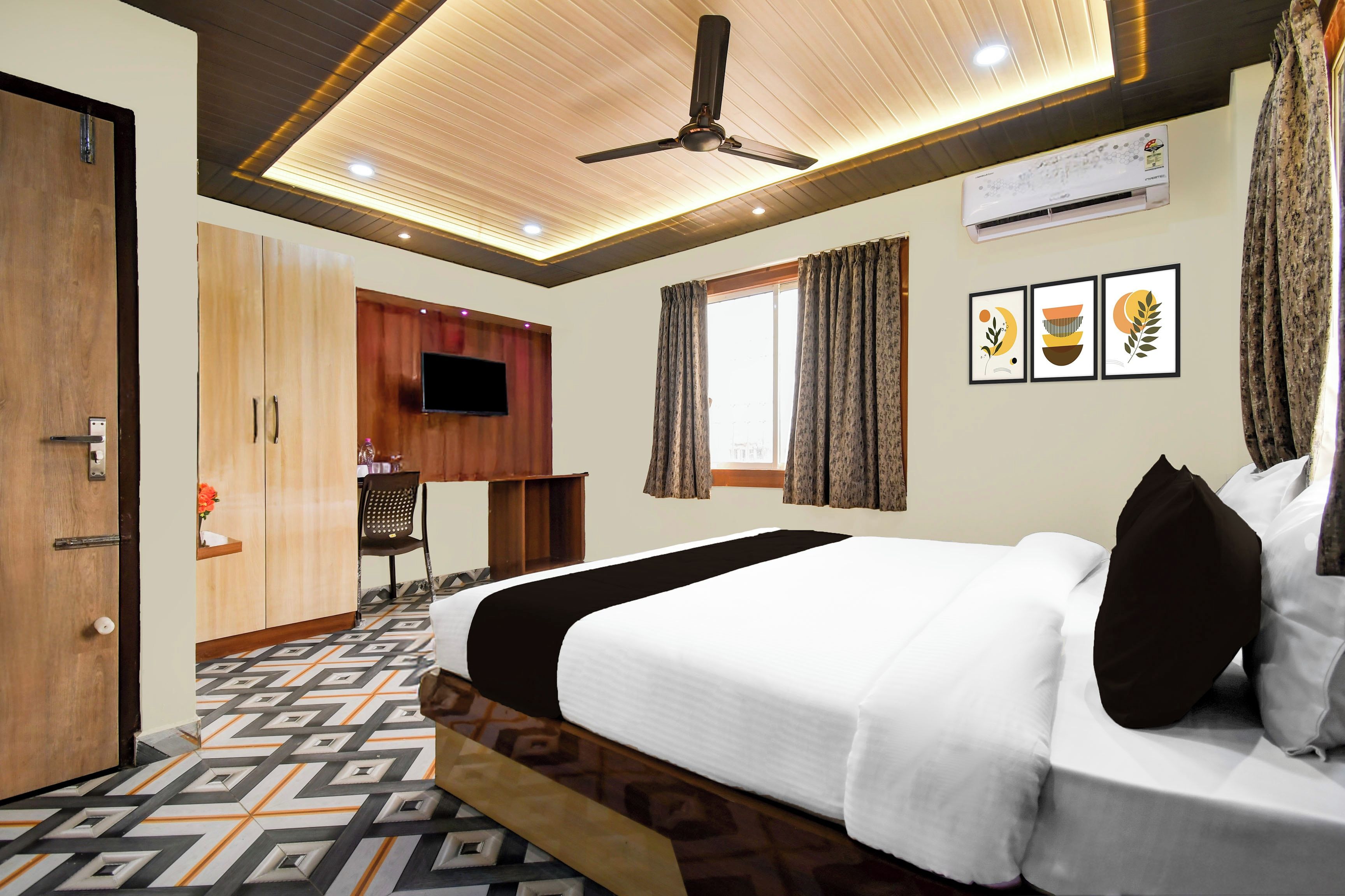 Ein Hotelzimmer mit einem Bett, einem Fernseher, einem Deckenventilator und einem Fenster mit Vorhängen.