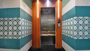 An elevator with a metallic interior and a control panel displaying floor numbers.