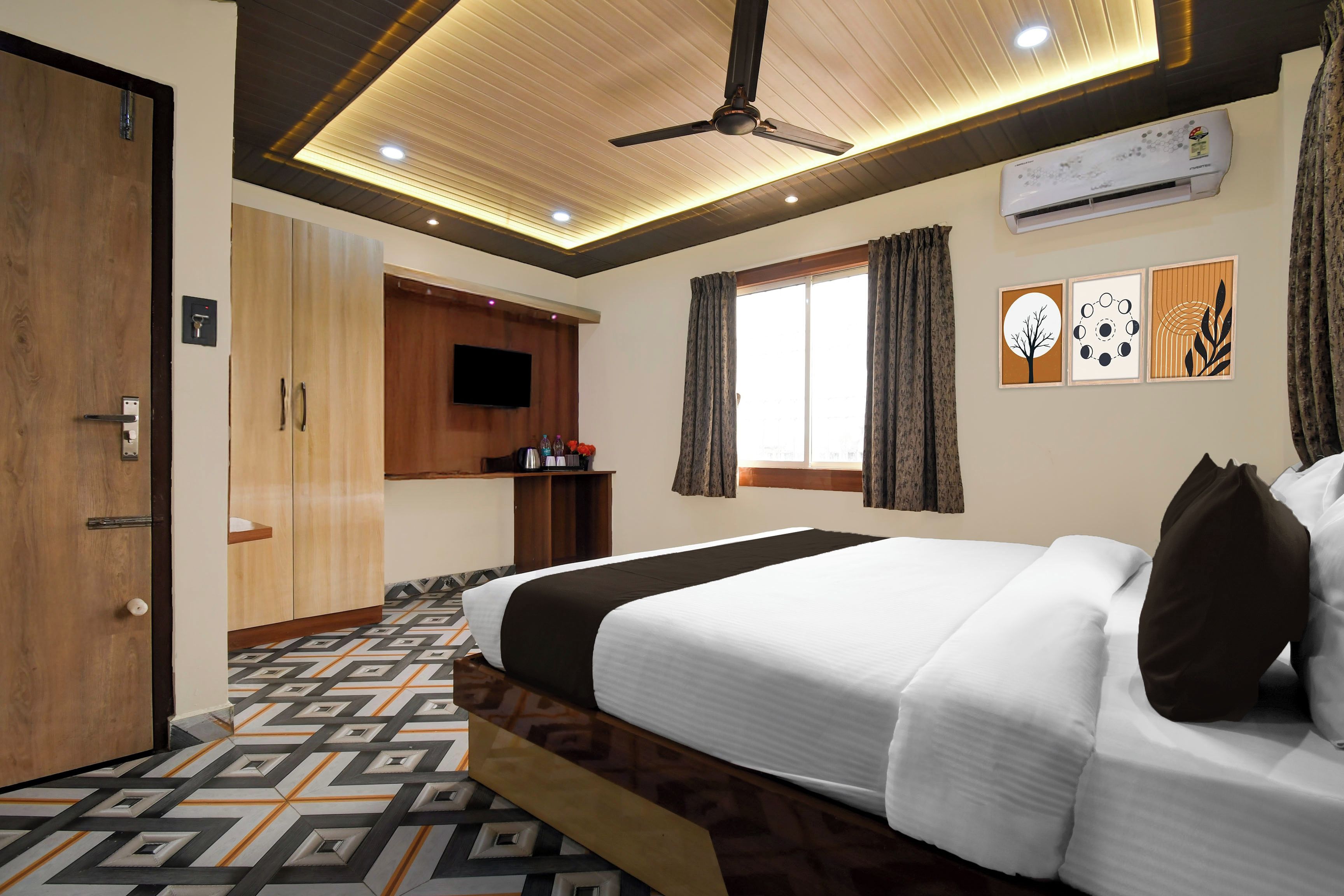 A hotel room with a bed, a ceiling fan, a TV, and a window with curtains.