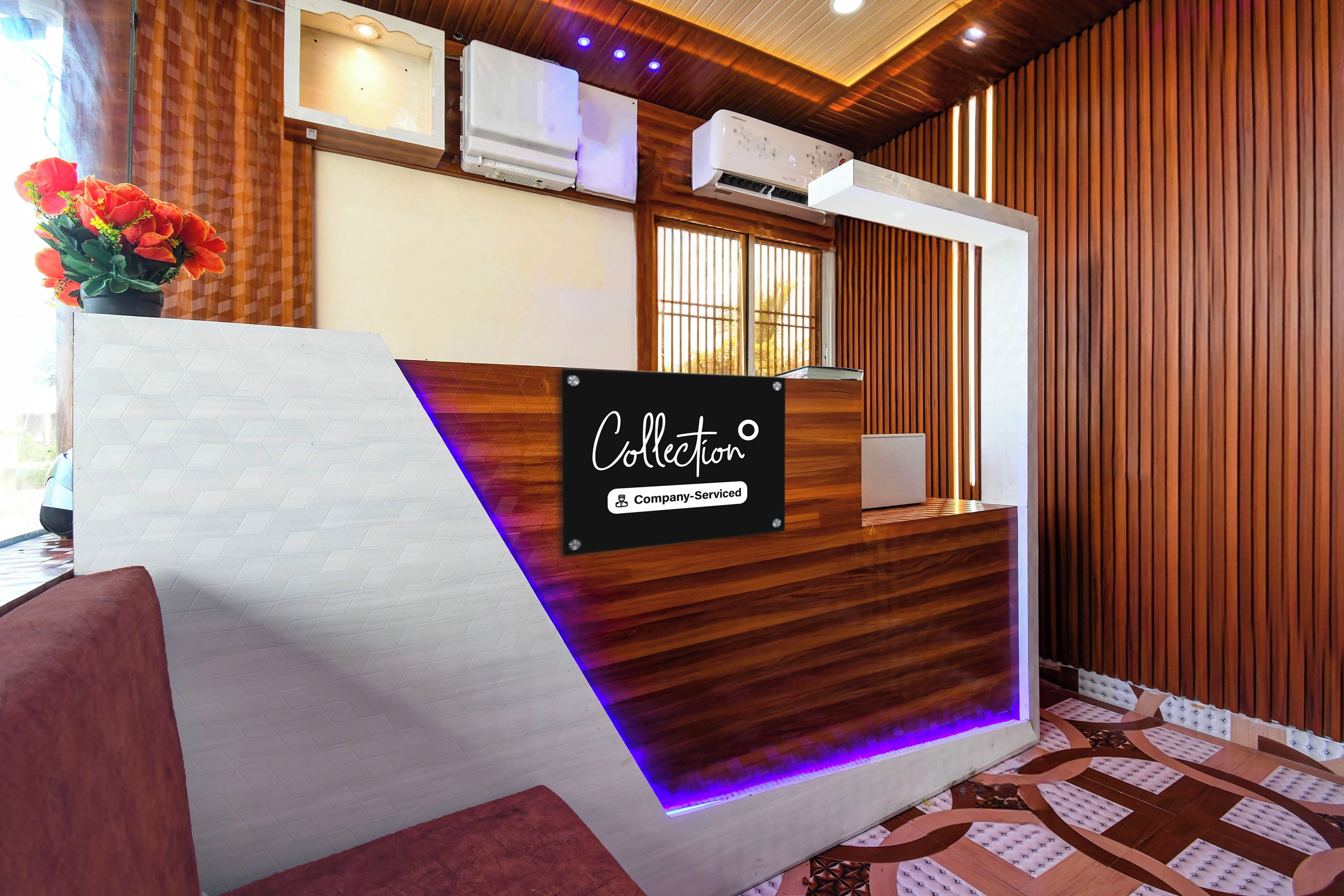 A reception desk with a sign indicating company-serviced amenities, air conditioning units, and a patterned floor.