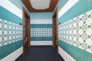 Un pasillo con paredes estampadas y suelo oscuro, que conduce a una habitación con techo de madera.