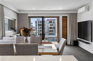 Habitació d'hotel moderna amb un balcó, televisió de pantalla plana i zona de menjador amb un ram d'flors seques.