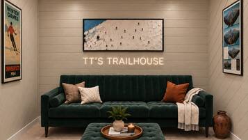 A cozy room with a green sofa, a coffee table with a plant, and a wall-mounted picture of a mountain landscape.