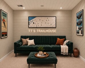 A cozy room with a green sofa, a coffee table with a plant, and a wall-mounted picture of a mountain landscape. - TT’s Trailhouse in Vail/BC: Ski Back • Hot Tub • Family + Dogs • EV Charger (Avon)