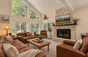 A spacious living room with leather sofas, a fireplace, and large windows. - TT’s Trailhouse in Vail/BC: Ski Back • Hot Tub • Family + Dogs • EV Charger (Avon)