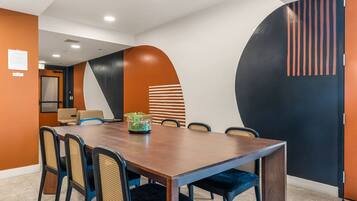 Un salón de conferencias con una larga mesa, sillas y un centro de mesa con planta decorativa.