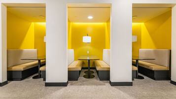 A modern interior with a central table and seating area, surrounded by walls with a yellow accent.