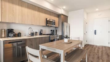 A modern kitchen with wooden cabinets, stainless steel appliances, and a dining area with a wooden table and chairs.