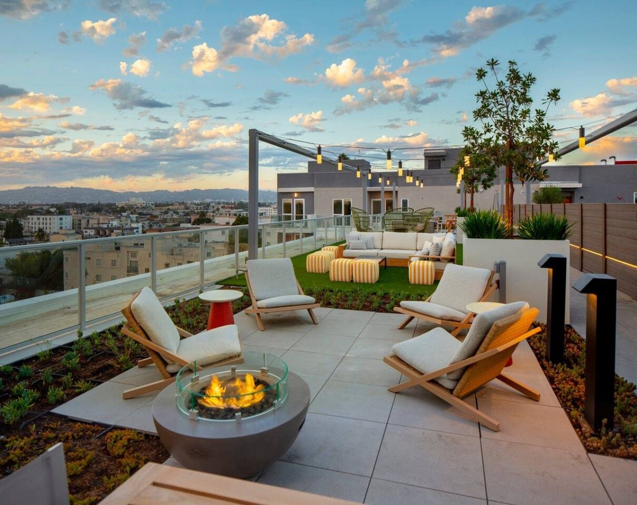 A rooftop terrace with outdoor seating, a fire pit, and a view of the cityscape.