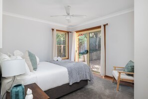 A bedroom with a bed, a nightstand, a chair, and a ceiling fan.
