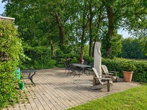 A patio area with a table and chairs, surrounded by greenery and trees. - Emsblick & Naturglück – Auszeit in Fresenburg (Fresenburg)