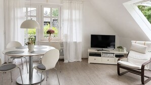 A modern living room with a dining area, a television, and a window with curtains. - Emsblick & Naturglück – Auszeit in Fresenburg (Fresenburg)
