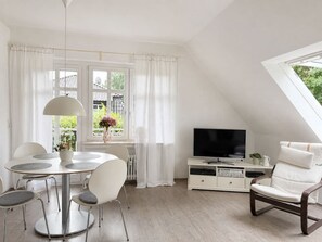 A modern living room with a dining area, a television, and a window with curtains. - Emsblick & Naturglück – Auszeit in Fresenburg (Fresenburg)
