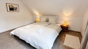 A bedroom with a large bed, two bedside tables with lamps, a framed picture on the wall, and a small rug. - Emsblick & Naturglück – Auszeit in Fresenburg (Fresenburg)