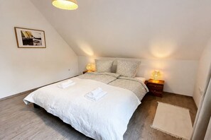 A bedroom with a large bed, two bedside tables with lamps, a framed picture on the wall, and a small rug. - Emsblick & Naturglück – Auszeit in Fresenburg (Fresenburg)