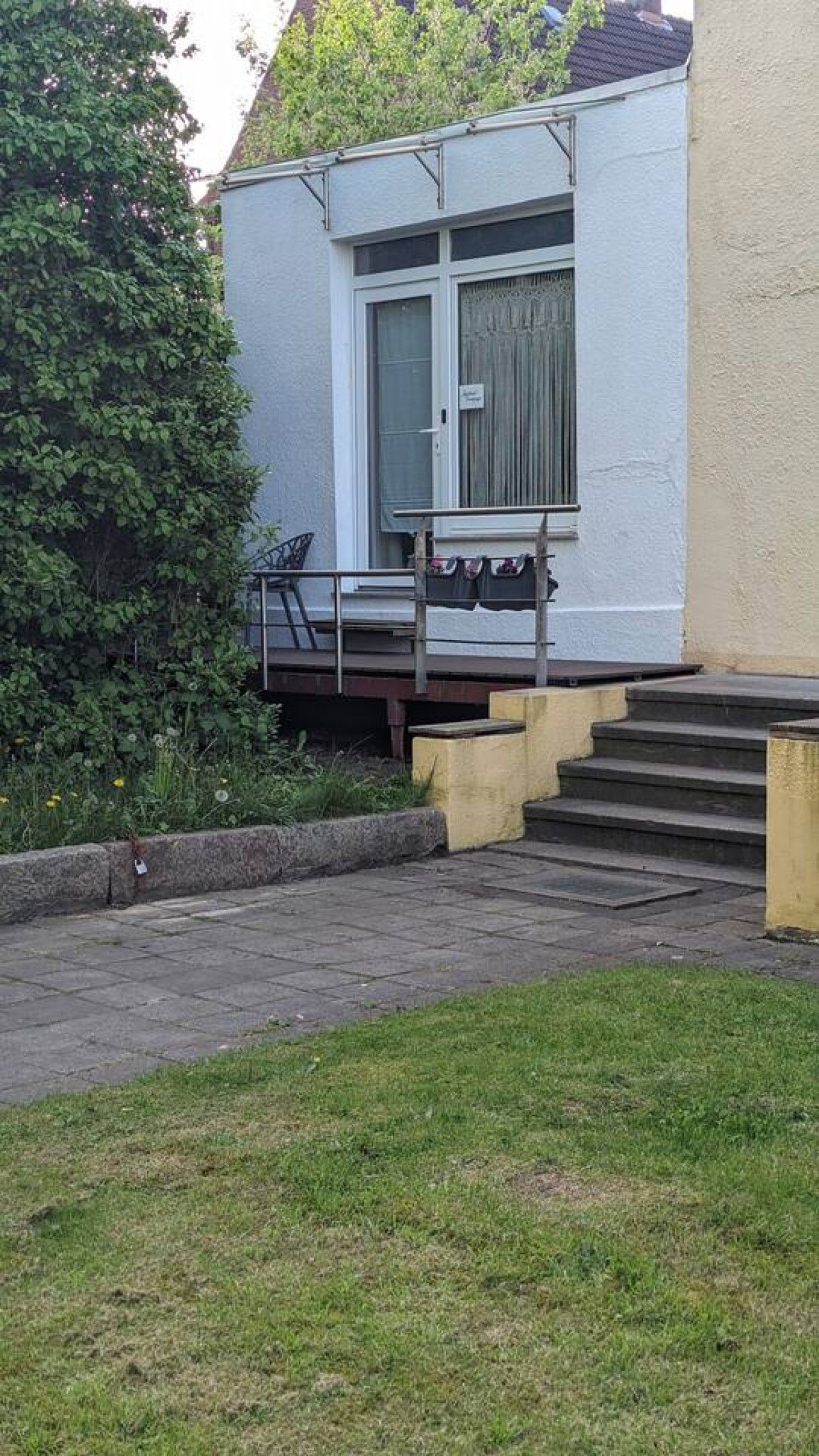 Un edifici residencial amb una porta d'entrada, un petit porxo i uns escalons que condueixen a l'accés.