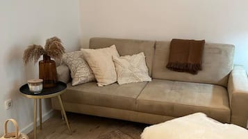 Ein modernes Wohnzimmer mit einer Couch, einem Beistelltisch, einem Teppich und Wandbildern.
