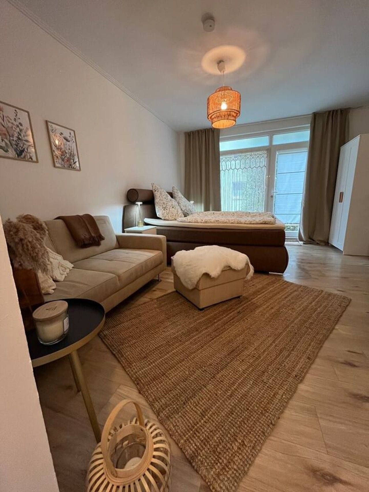 Ein modernes Schlafzimmer mit einem Bett, einem Sofa, einem kleinen Tisch und einem dekorativen Teppich.
