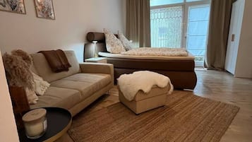 Ein modernes Schlafzimmer mit einem Bett, einem Sofa, einem kleinen Tisch und einem dekorativen Teppich.