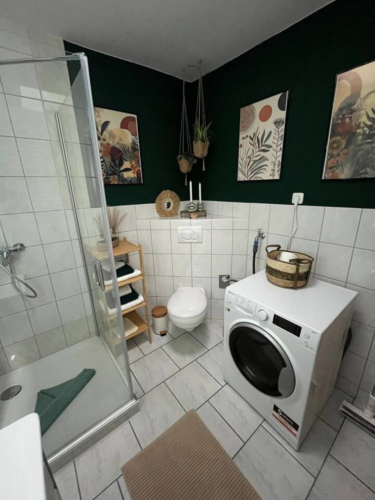 Ein kleines Badezimmer mit Duschkabine aus Glas, einer Waschmaschine und einer Toilette.