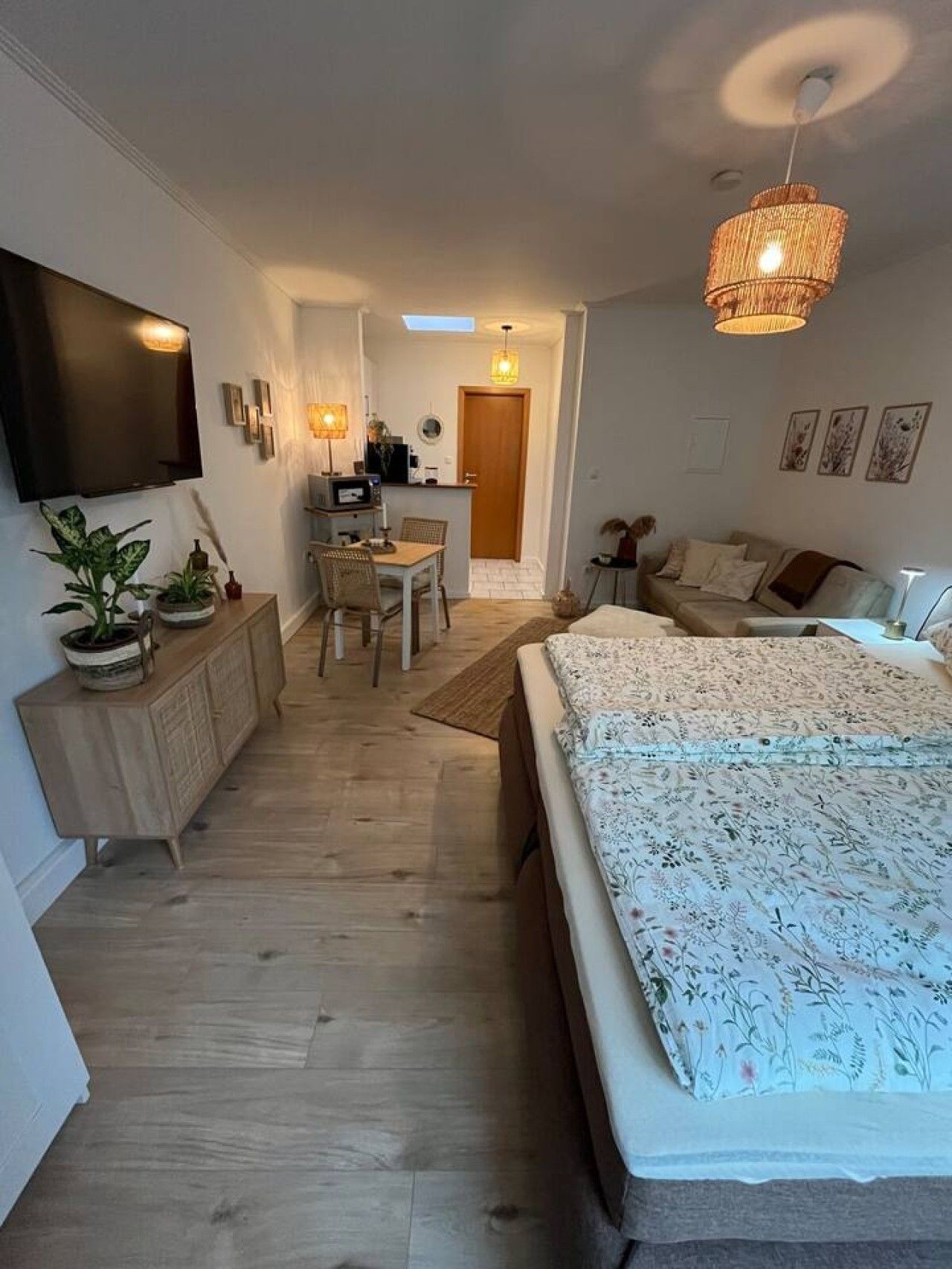 Een moderne slaapkamer met een groot bed, een bureau en een aan de muur bevestigde televisie.