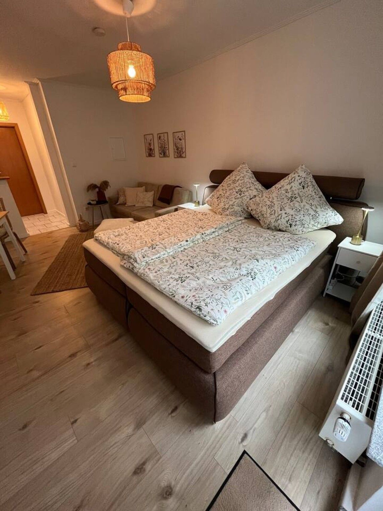 Een slaapkamer met een groot bed, nachtkastjes, een hanglamp en een radiator.