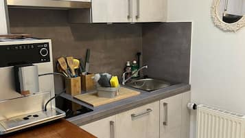 Cuina amb fogó integrat, un rentaplat i una encimera amb taula de tall i utensilis.