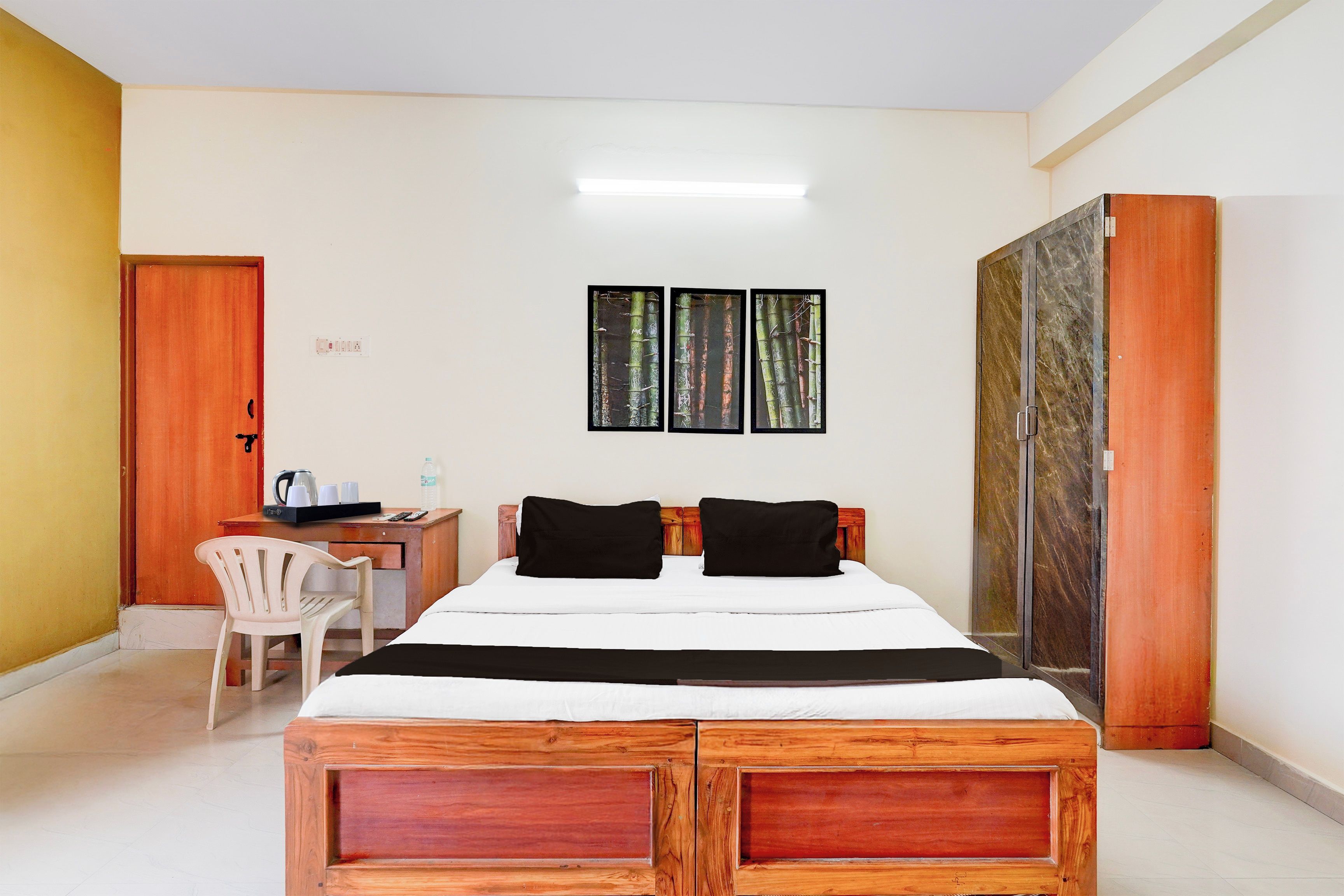 A hotel room with a wooden bed, a desk with a chair, and a wardrobe.
