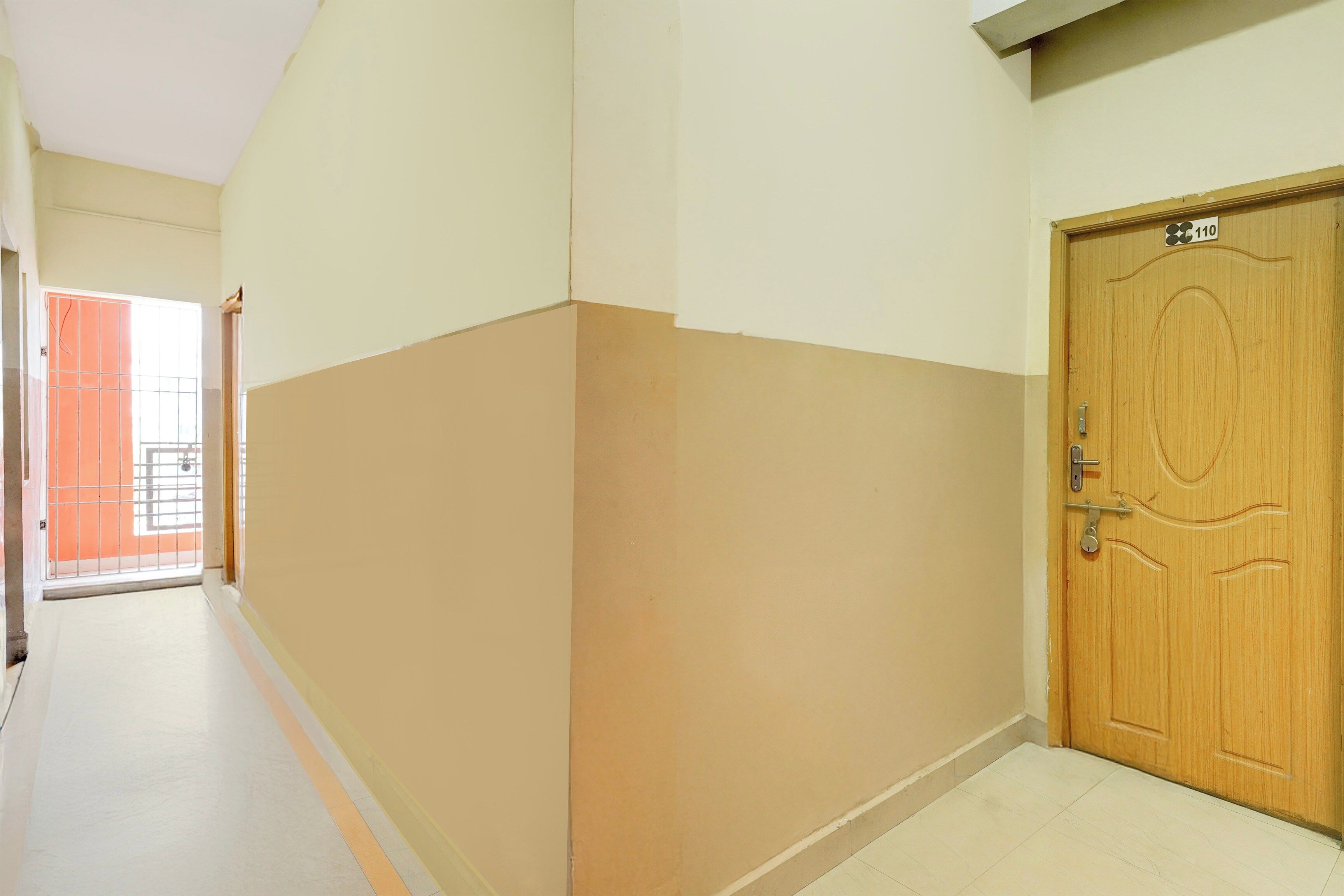 A corridor with a wooden door, beige walls, and a tiled floor.