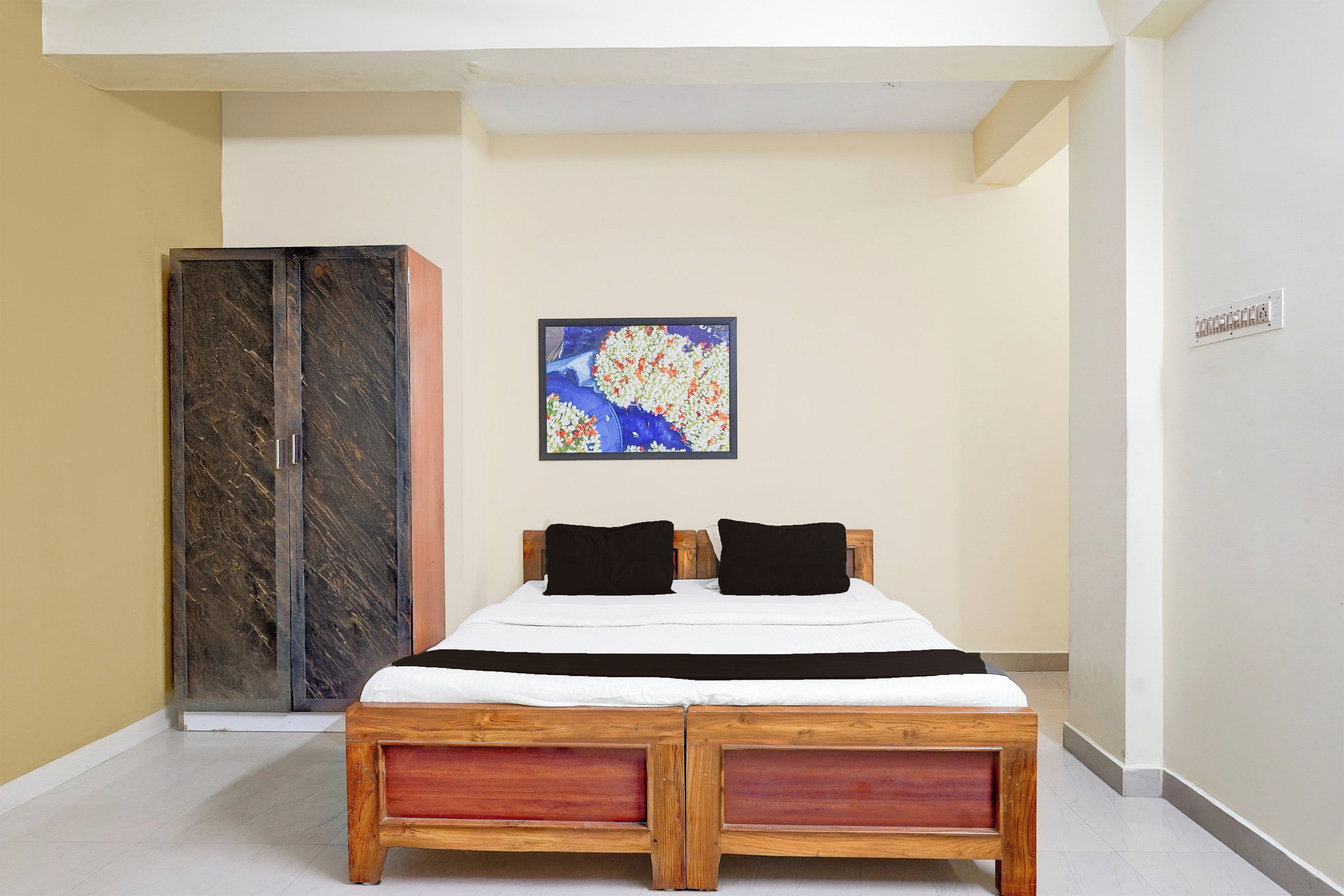 A bedroom with a bed, a wardrobe, and a painting on the wall.