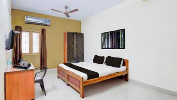 A bedroom with a bed, a desk, a chair, an air conditioner, a wardrobe, and a ceiling fan.
