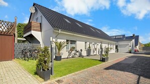 Et moderne hus med to etager, skråt tag, indkørsel og en velplejet græsplæne.