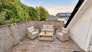 Eine Terrasse im Freien mit Korbmöbeln und einem Holztisch.