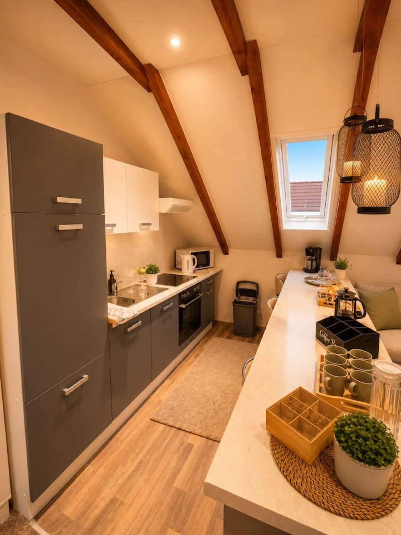 Una cocina moderna con armarios oscuros, una isla central y un ventanal sobre el lavabo.