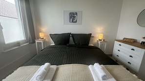 Ein Schlafzimmer mit einem Bett, zwei Nachttischen, einer Kommode und einem Wandbild.