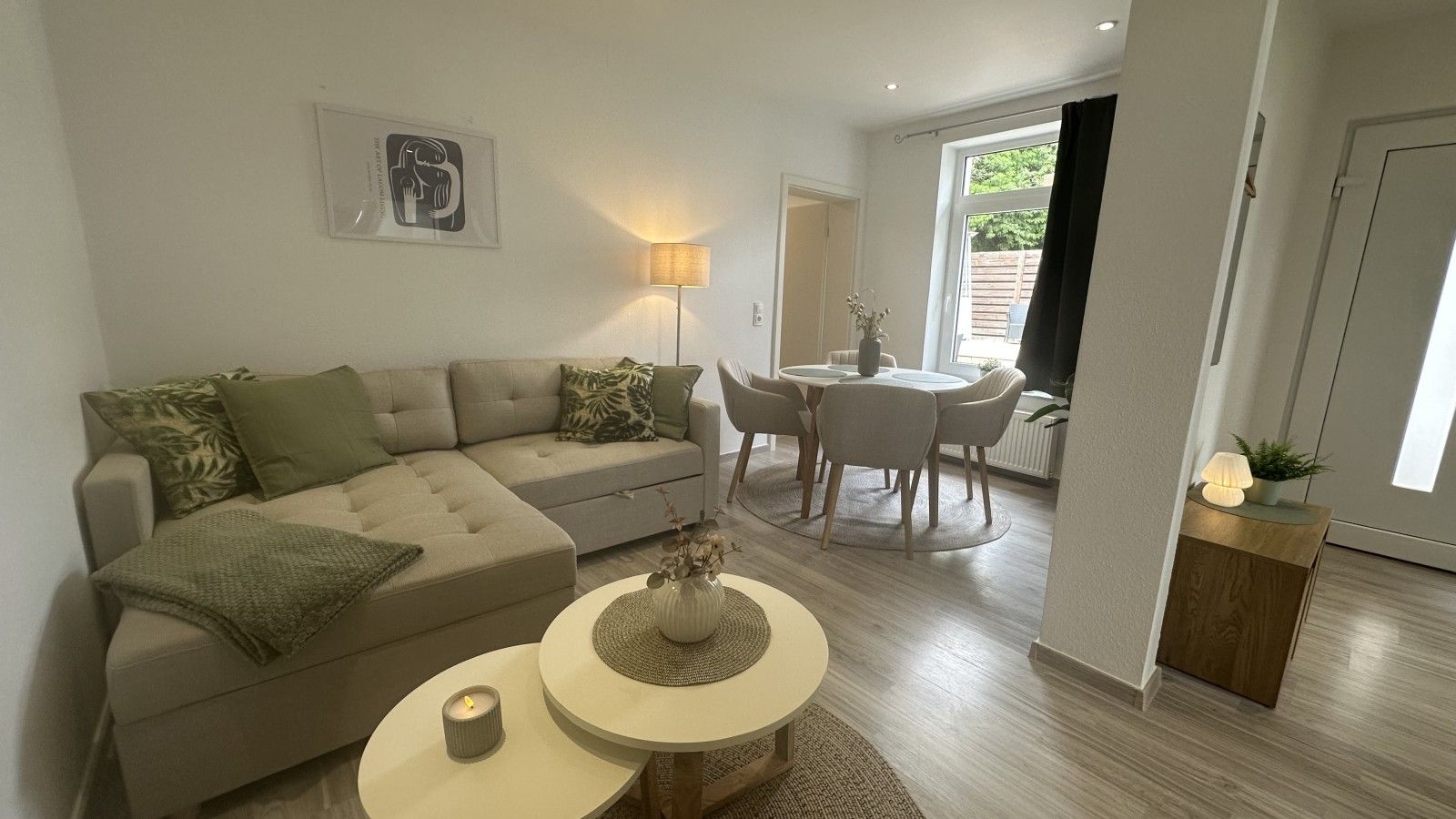 A modern living room with a sectional sofa, a round coffee table, and a dining area with a table and chairs.