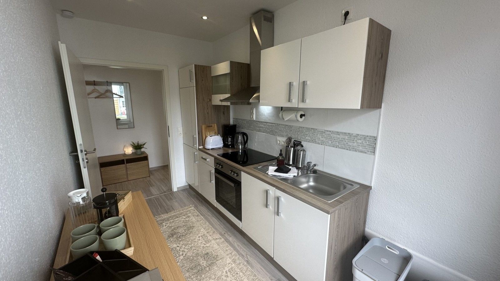 A compact kitchen with a built-in oven, a sink, and a coffee maker.