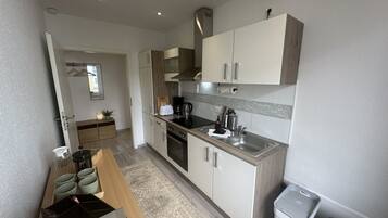 A compact kitchen with a built-in oven, a sink, and a coffee maker.