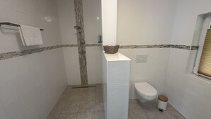 Et badeværelse med bruser, toilet og et håndklædetørrestativ.